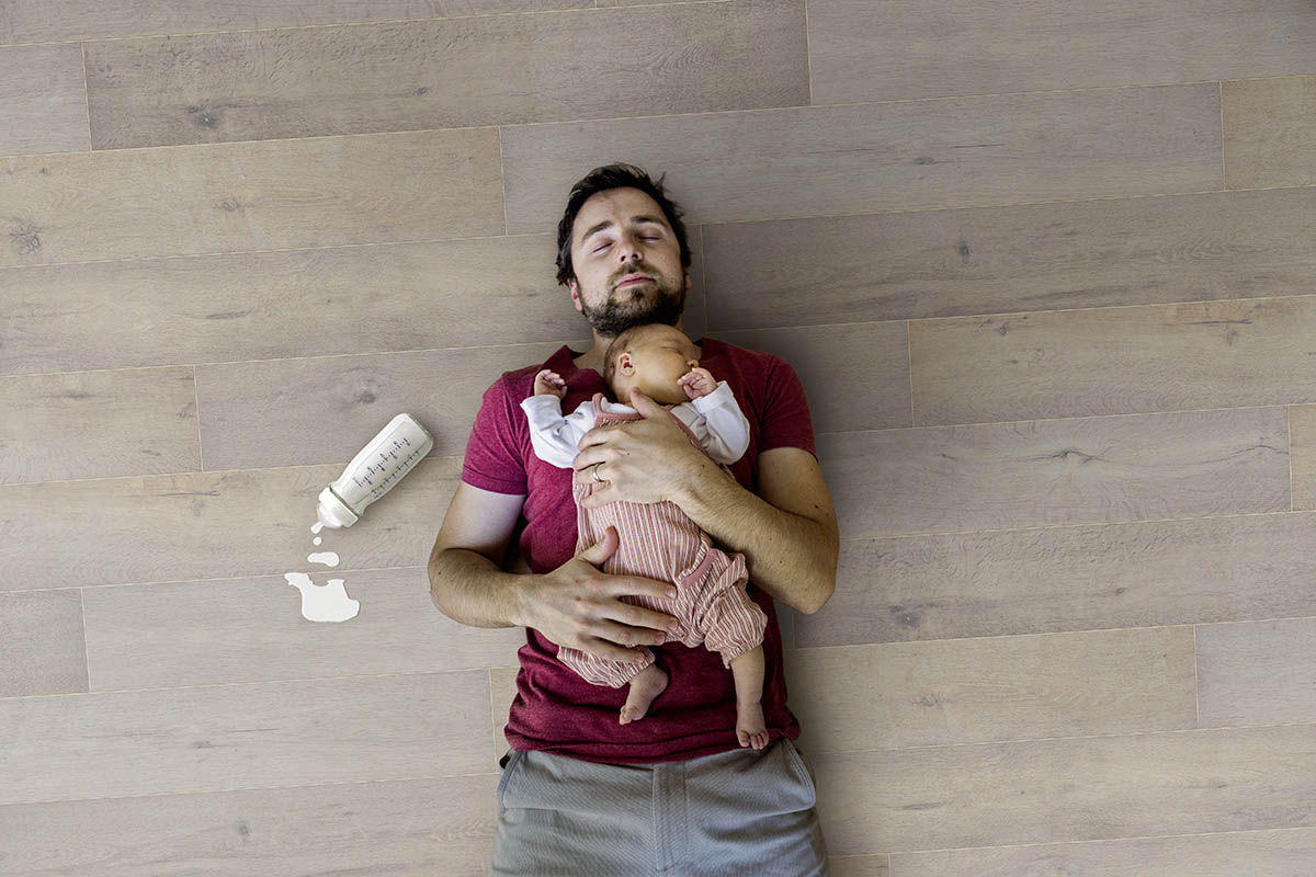 Father holding newborn baby girl, wooden background.